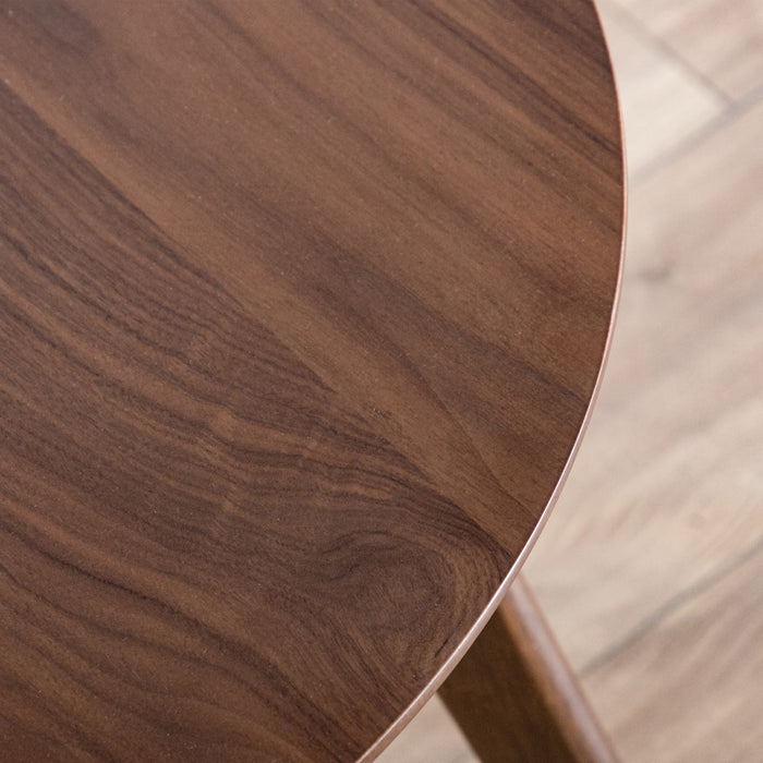 Close up view of the tabletop of a mid-century modern walnut finish round wood side table with splayed legs