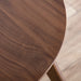 Close up view of the tabletop of a mid-century modern walnut finish round wood side table with splayed legs