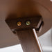 Close up view of the leg attachment under the tabletop of a mid-century modern walnut finish round wood side table with splayed legs