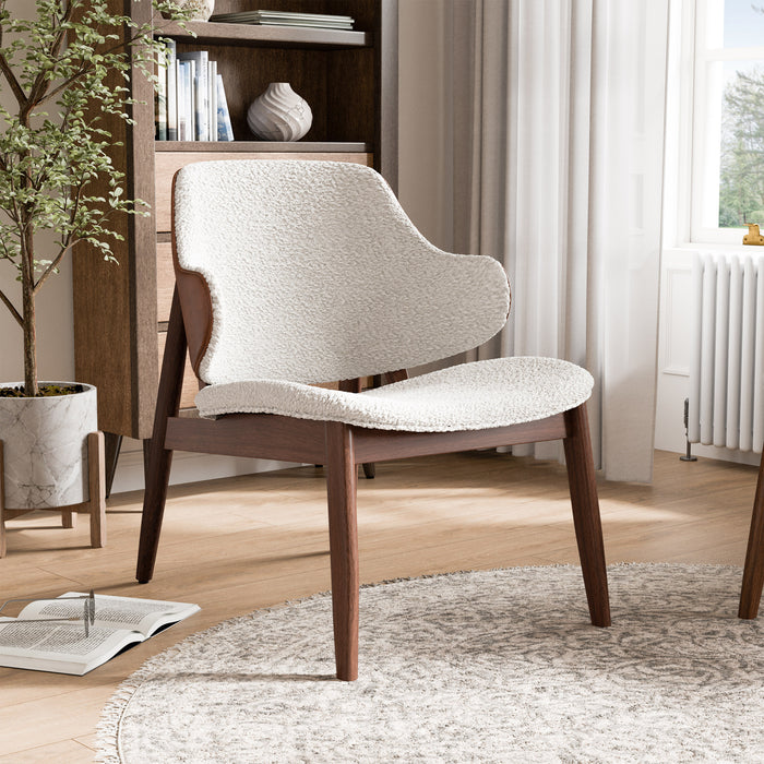 Right facing mid-century modern walnut and ivory boucle accent armchair in a room with accessories