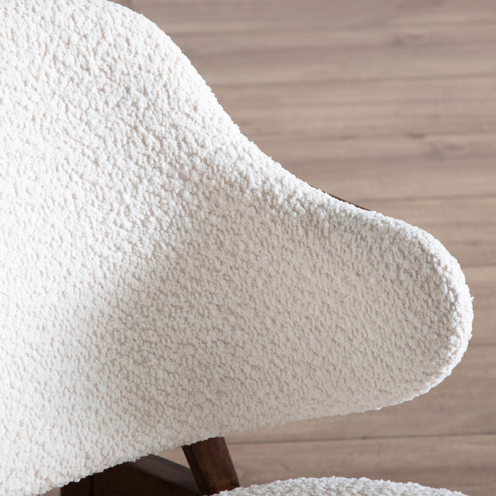 Right facing close up of the backrest of a mid-century modern walnut and ivory boucle accent armchair in a room