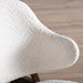 Right facing close up of the backrest of a mid-century modern walnut and ivory boucle accent armchair in a room