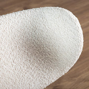 Right facing close up of the wingback of a mid-century modern walnut and ivory boucle wingback accent chair in a room