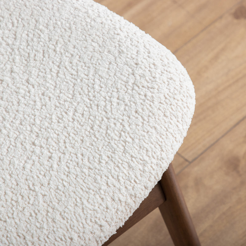 Right facing close up of the seat of a mid-century modern walnut and ivory boucle wingback accent chair in a room