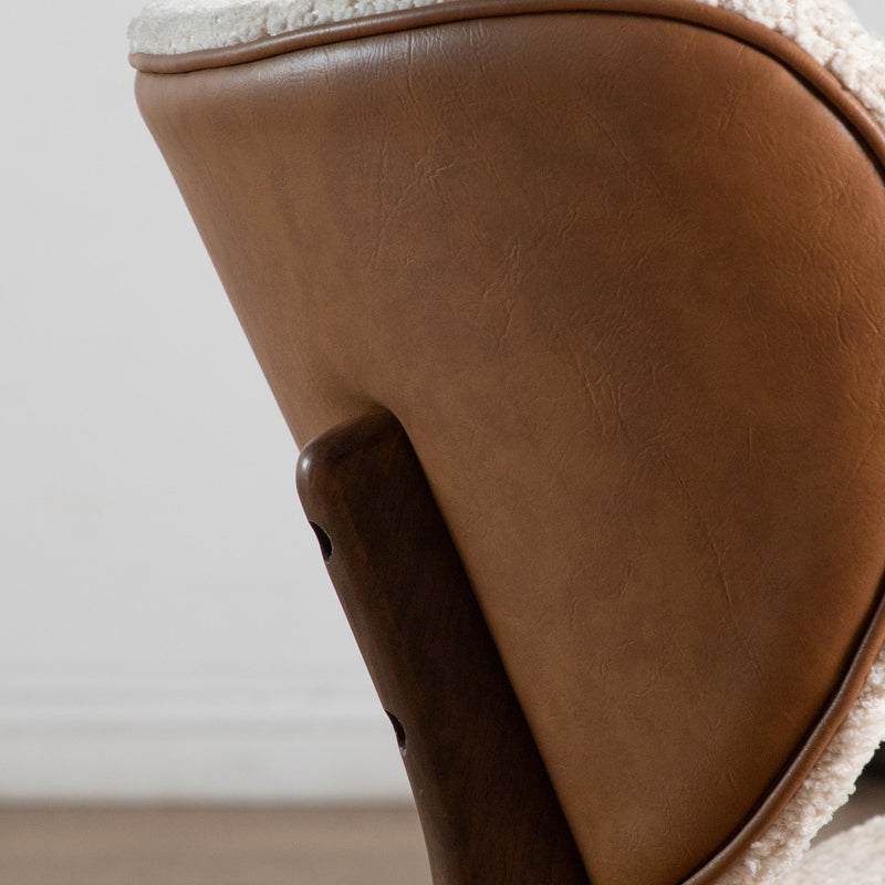 Front facing close up side view of the backrest of a mid-century modern walnut and ivory boucle wingback accent chair in a room