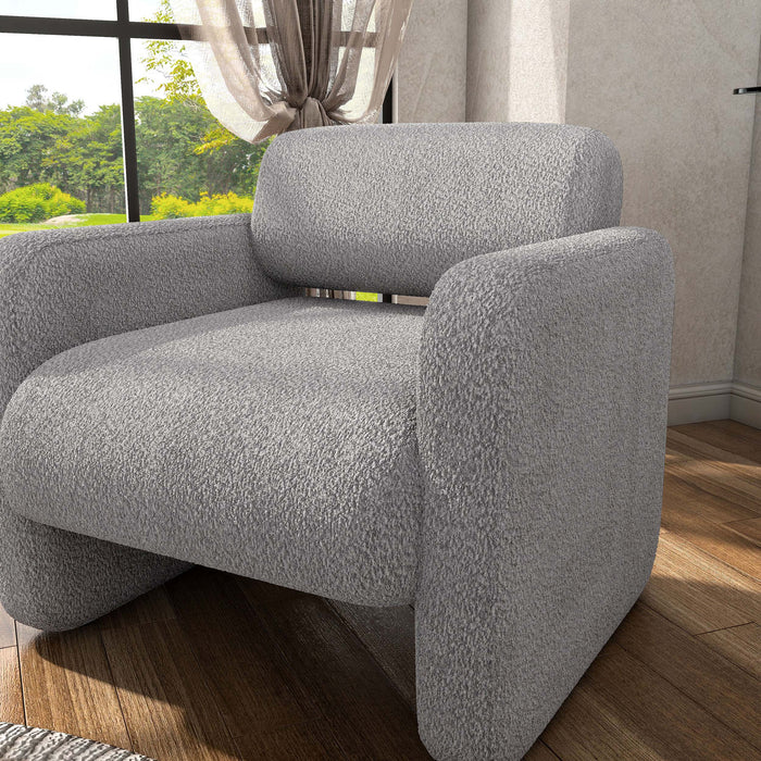 Left facing contemporary gray boucle upholstered accent armchair in a room with accessories