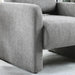 Right facing close up view of the arm and seat on a contemporary gray boucle upholstered accent armchair in a room with accessories