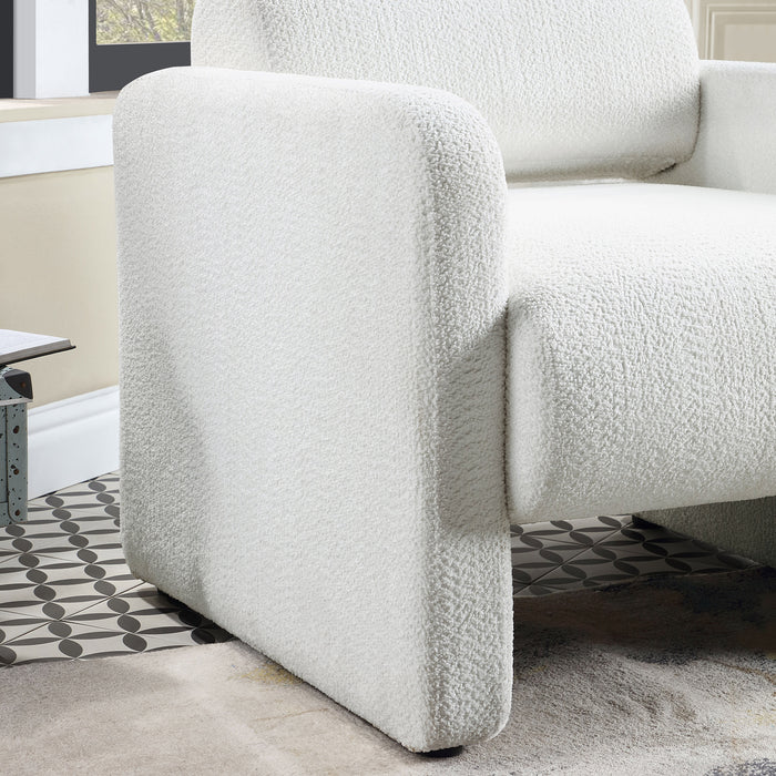Right facing close up view of the arm and seat of a contemporary white boucle upholstered accent armchair in a room