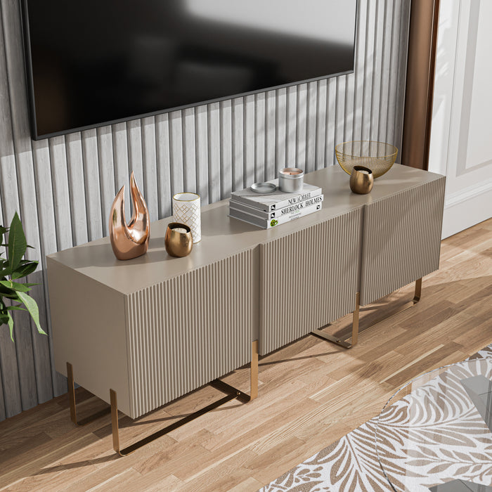Right facing bird's eye view of a contemporary light taupe and vintage gold fluted three-door TV stand in a room with accessories