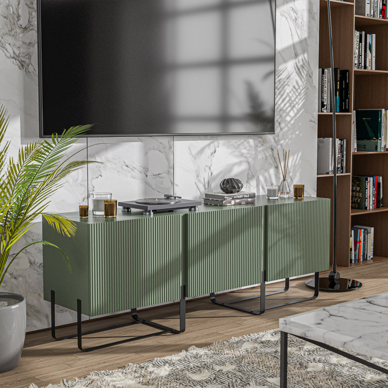 Right facing contemporary sage green and black fluted three-door TV stand in a room with accessories