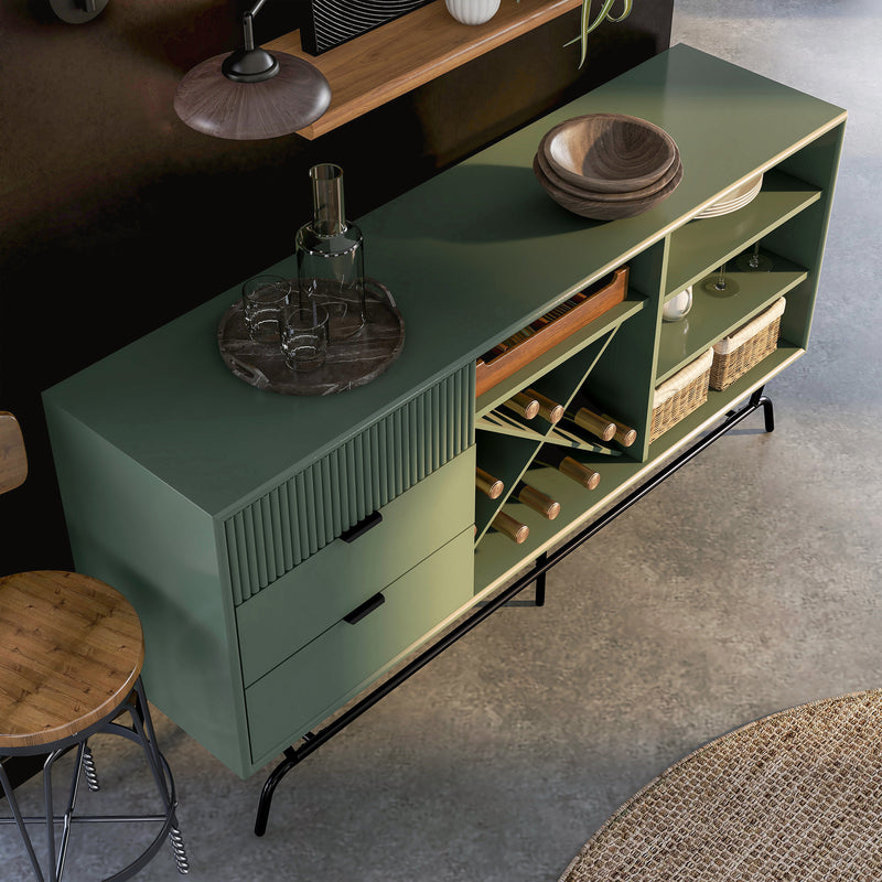 Right facing bird's eye view of a contemporary three-drawer sage green and black TV stand with a wine rack in a room with accessories