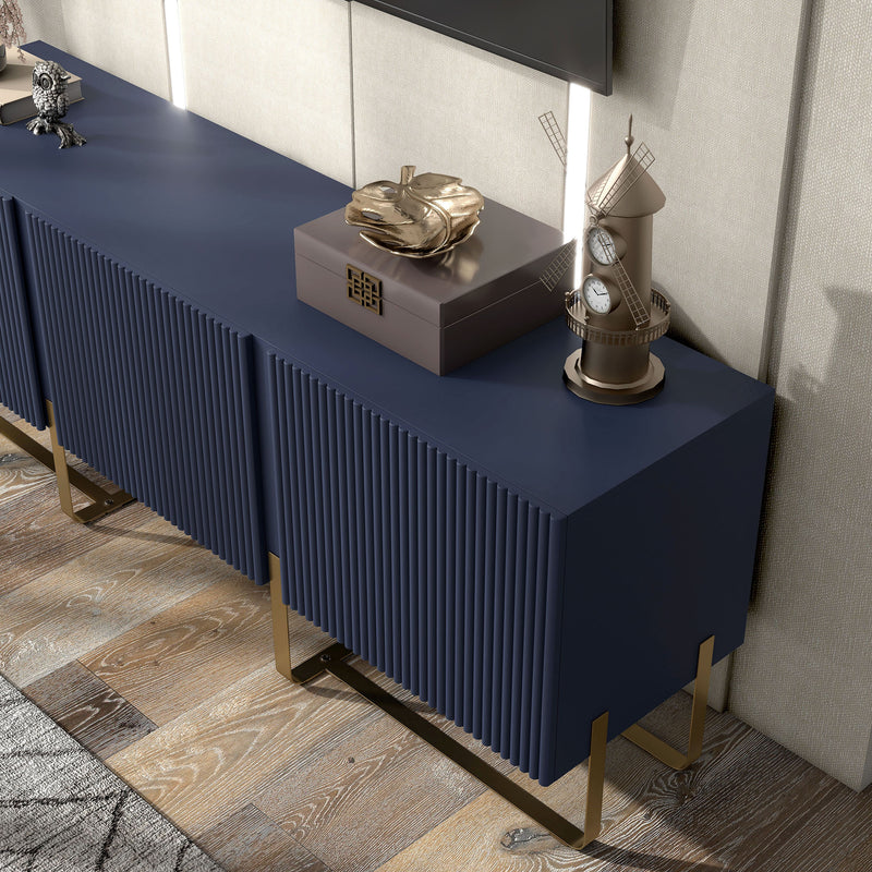 Left facing bird's eye close up view of a contemporary indigo blue and vintage gold fluted three-door TV stand in a room with accessories