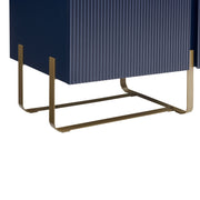 Right facing close up view of the door and leg of a contemporary indigo blue and vintage gold fluted three-door TV stand on a white background