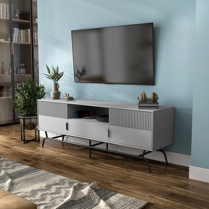 Left facing contemporary grey and black three-drawer two-door TV stand with fluting in a room with accessories