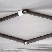 Close up of the support structure of a transitional burgundy outdoor pop-up canopy with one shade wall