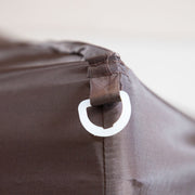 Close up of the corner anchor for tie-down of a transitional burgundy outdoor pop-up canopy with one shade wall