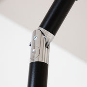 Close up of the tilt mechanism of a contemporary blue outdoor auto tilt umbrella with a carrying case on white background