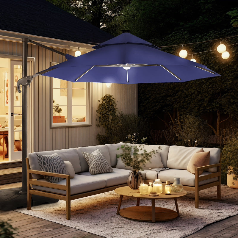 Right facing contemporary cantilever umbrella in navy blue fabric with solar LED lighting and carrying case at night on a patio with accessories