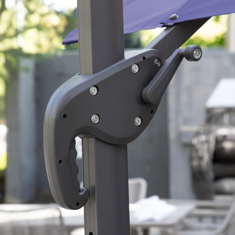 Right facing close up of the crank mechanism on a contemporary cantilever umbrella in navy blue fabric with solar LED lighting and carrying case on a patio