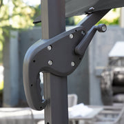 Right facing close up of the crank mechanism on a contemporary cantilever umbrella in grey fabric with solar LED lighting and carrying case on a patio