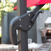Right facing close up of the crank mechanism on a contemporary cantilever umbrella in red fabric with solar LED lighting and carrying case on a patio