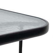 Close up of the rounded corner of a transitional black and textured glass patio outdoor dining table on a white background