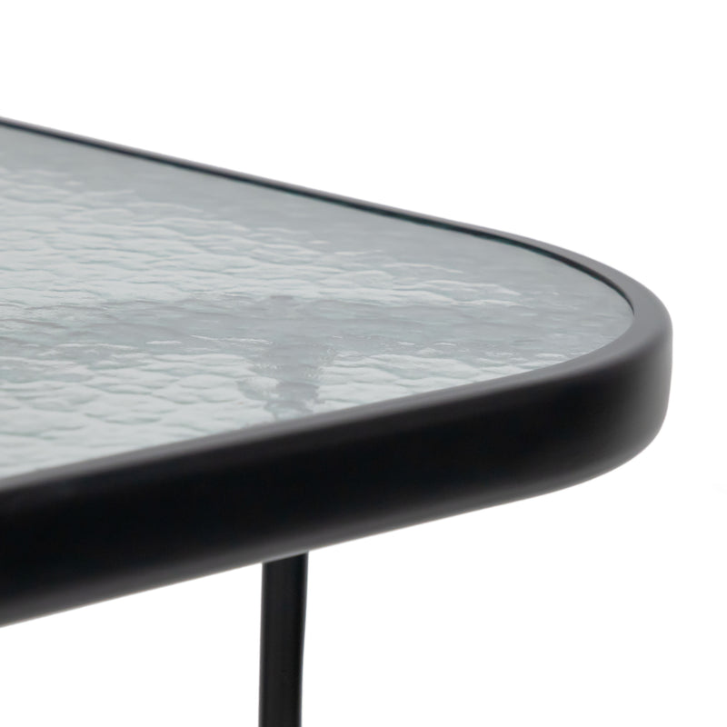 Close up of the rounded corner of a transitional black and textured glass patio outdoor dining table on a white background
