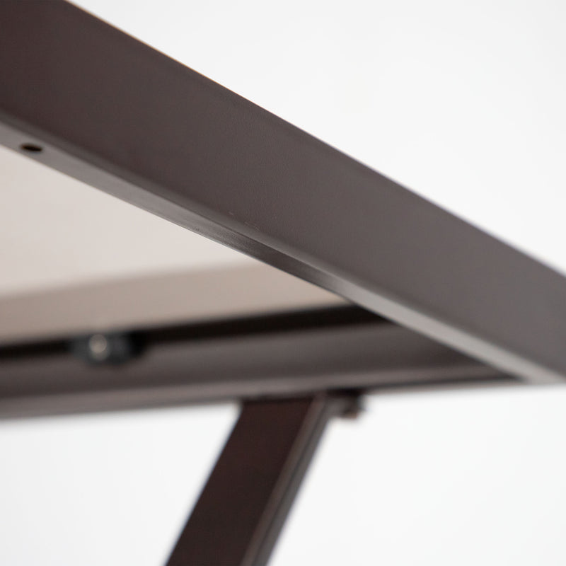 Close up of the tabletop edge of a four-piece transitional beige outdoor patio seating set with a table, two chairs, and a loveseat on a white background