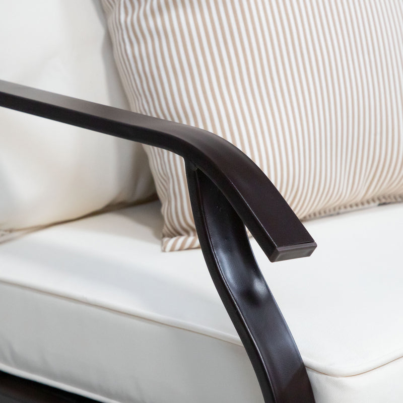 Close up of the armrest and cushions of a four-piece transitional beige outdoor patio seating set with a table, two chairs, and a loveseat