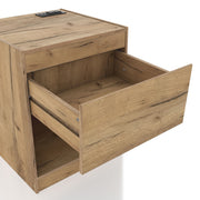 Right facing rustic light oak one-drawer nightstand with an open shelf and a charging port in the tabletop shown with drawer open on a white background
