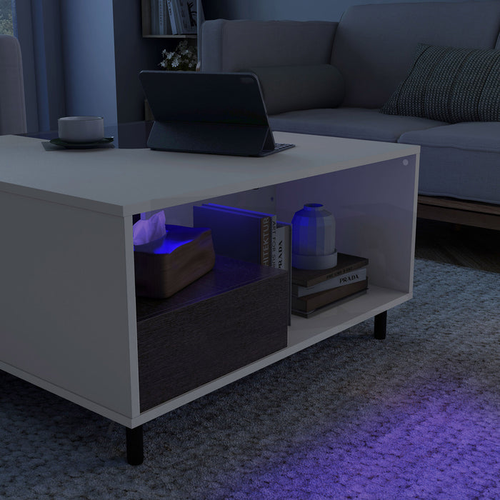 Left facing close up of a contemporary white and brown storage coffee table with a glass inset and LED lighting in a room with accessories