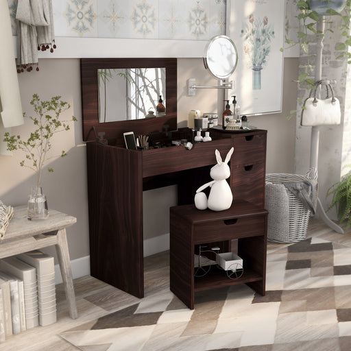Right-angled walnut vanity table set with stool in a contemporary bedroom. The lift-top table reveals an underside mirror and compartmentalized storage. Two grooved handles on the table and one grooved handle on the stool indicate more storage space.