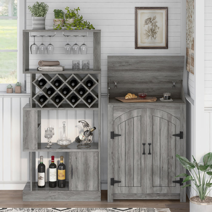 Front-facing of a vintage grey oak wine bar against a shiplap wall. Wine glasses hang on the stemware racks and 11 wine bottles nestle in the trellis wine rack. The roof of the bar is lifted to offer a shelf for a cutting board with a croissant and jam. A glass of coffee also rests on the counter.