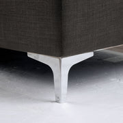 Left angled close up contemporary gray storage chaise with detail of sleek chrome legs on a white background