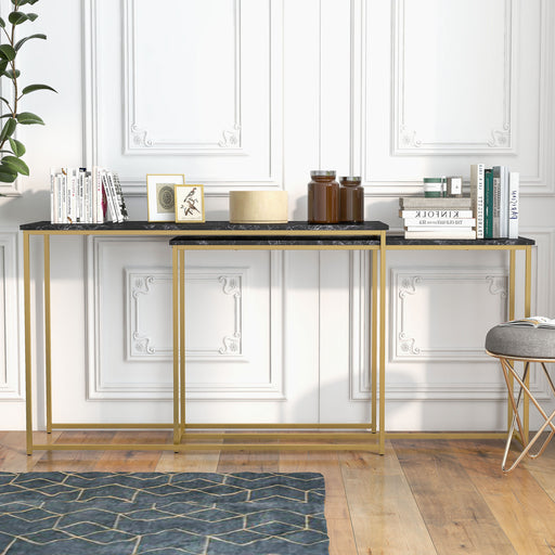 Straight-facing faux black marble nesting tables with gold-tone frames against a molded white wall. An assortment of books, picture frames, and decor adorn the tabletops.