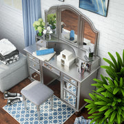 Top view of a silver vanity set in a blue themed youth bedroom. Make-up adorns the vanity table as the silver set mingles with the blue accents of the room. A blue curtain hangs to the left and the stool sits on a blue patterned rug.