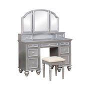 Right-angled silver vanity set against a white background. This vanity table offers a tri-fold mirror and a total of nine drawers. Bun feet hold up the vanity table, while turned legs prop up a fabric-top stool.