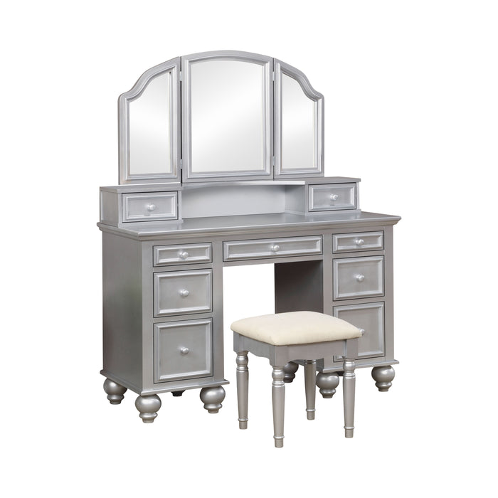 Right-angled silver vanity set against a white background. This vanity table offers a tri-fold mirror and a total of nine drawers. Bun feet hold up the vanity table, while turned legs prop up a fabric-top stool.