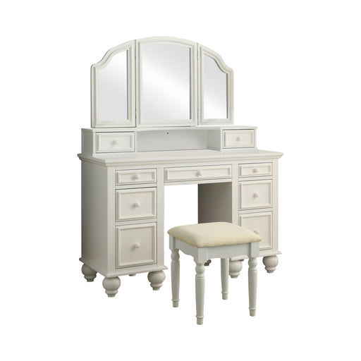 Right-angled white vanity set against a white background. This vanity table offers a tri-fold mirror and a total of nine drawers. Bun feet hold up the vanity table, while turned legs prop up a fabric-top stool.