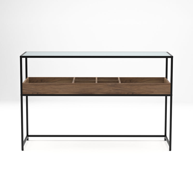 Straight-facing mixed material console table against a white background. A matte black steel frame holds a glass top for an open and airy design. Below the tabletop is a compartmentalized shelf. Two large compartments flank four smaller compartments in a warm wood color.