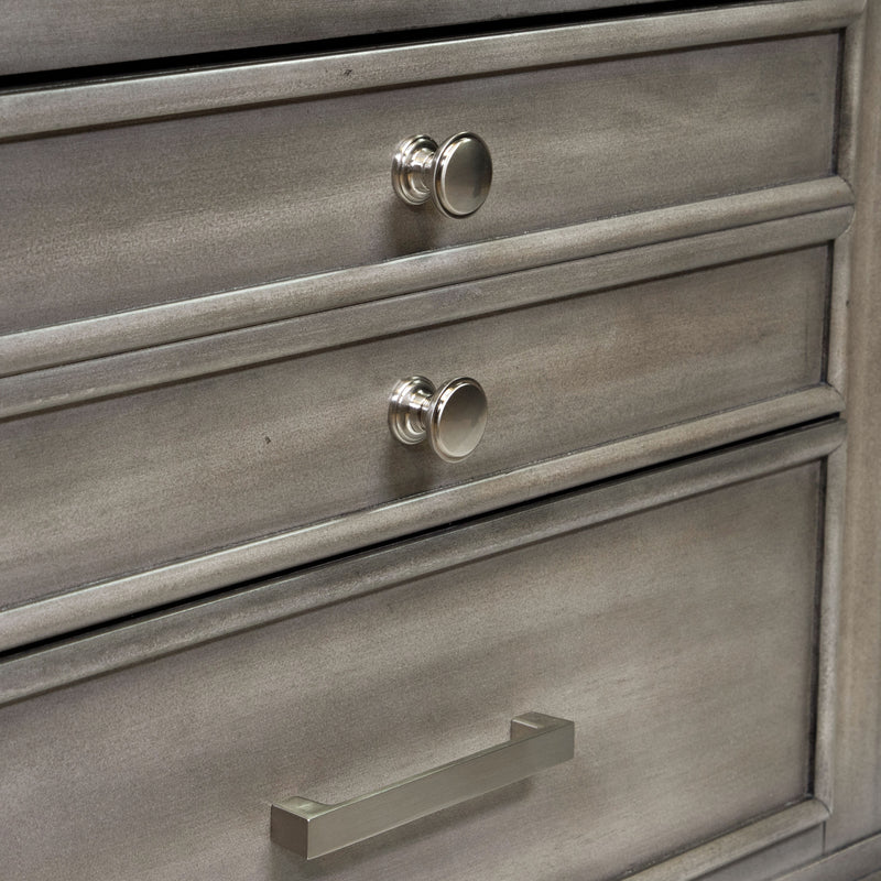 Detail shot of the drawer fronts of a transitional grey 2-drawer nightstand. The top drawer has a double-drawer facet with two silver knobs to contrast the lower drawer with a silver bar pull.