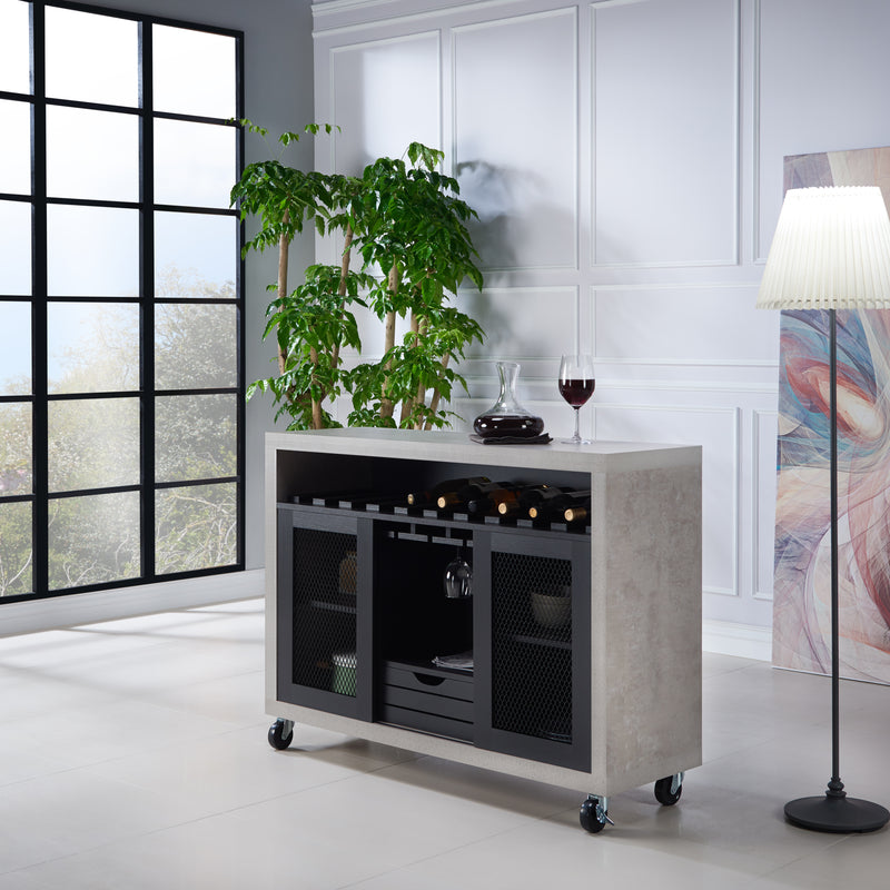 Left-angled cement and black wine bar cabinet against a white background. The 10 slots beneath the tabletop hold wine bottles, while the 3 stemware racks hang wine glasses. A plank-style drawer is flanked by wire-mesh cabinets. The entire buffet sits on wheels with parking brakes.