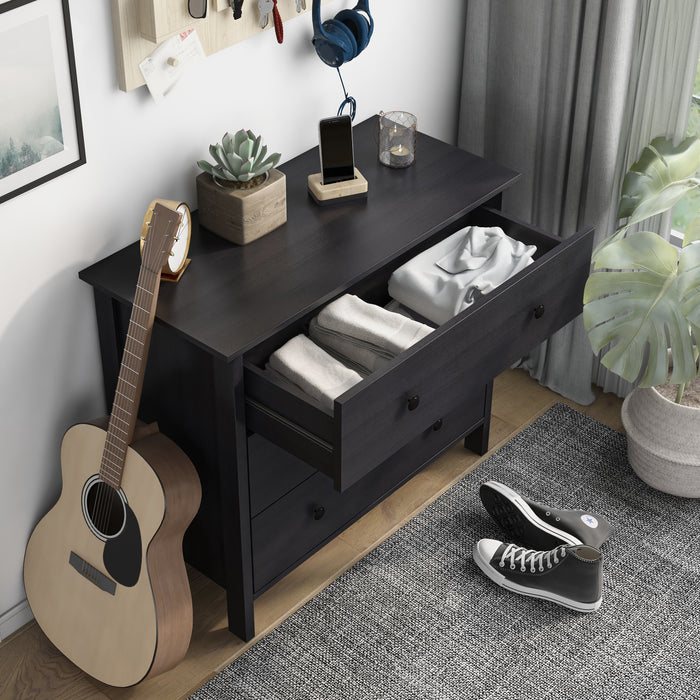 Right-angled top view transitional three-drawer dresser in black wood grain with center drawer open in a contemporary bedroom with accessories