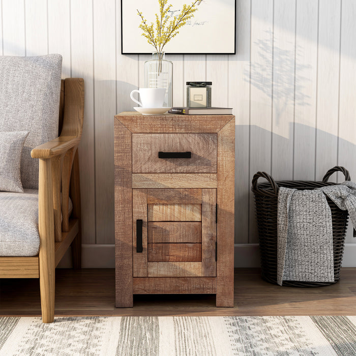 Front-facing solid mango wood side table in a beach house. The unfinished sawblade design and black bar pulls add a casual look to the shiplap white wall. A black frame hangs above the end table while a black basket sits to its right. A vase of yellow flowers, a book, and a macchiato sit on the table next to a sofa.