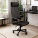 Angled view of modern black fabric and metal adjustable office chair in work space with furnishings and accessories