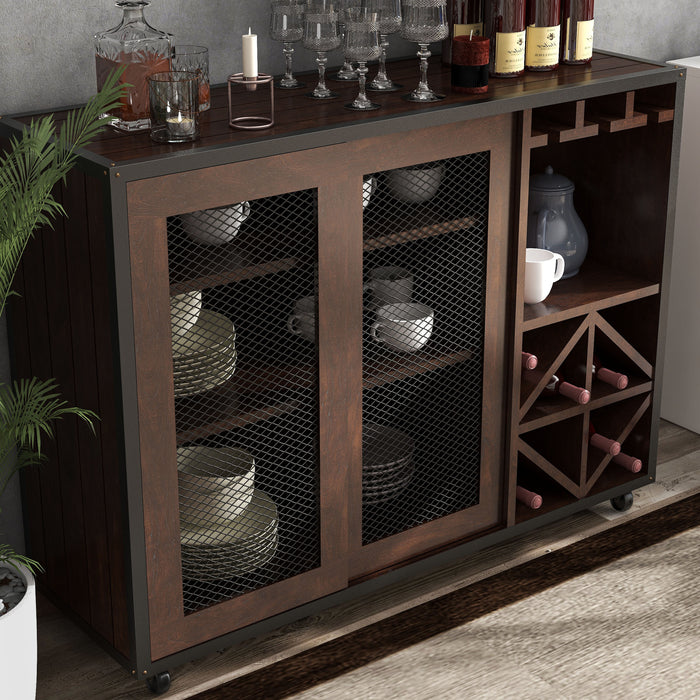 Top view of a vintage walnut wine bar cabinet in an entertainment space creates a mini home bar. A decanter and glasses sit on the plank-style tabletop. Behind the wire mesh cabinet doors are cups and plates. The wine rack holds wine bottles.