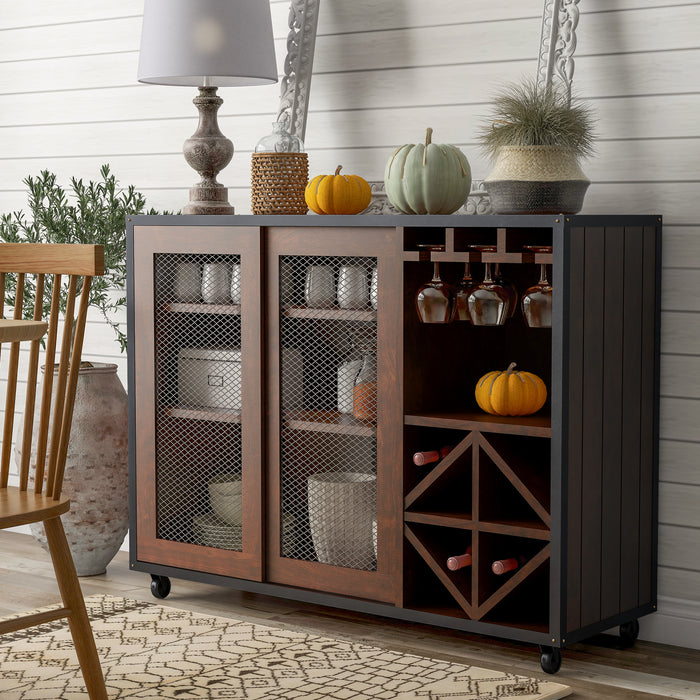 Left-angled vintage walnut wine bar cabinet in a country farmhouse style dining room. A lamp and decorative pumpkins sit on the tabletop. Behind the wire mesh cabinet doors are cups and plates. Orange wine glasses hang on stemware racks while wine bottles are stored in the wine rack.