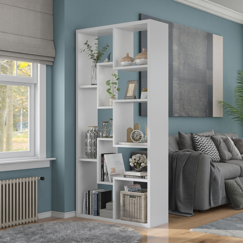 Left angled modern white geometric bookcase with staggered shelves as a room divider with accessories