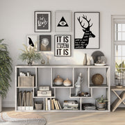 Front-facing modern vintage gray oak geometric bookcase with staggered shelves laid horizontally in a living area with accessories