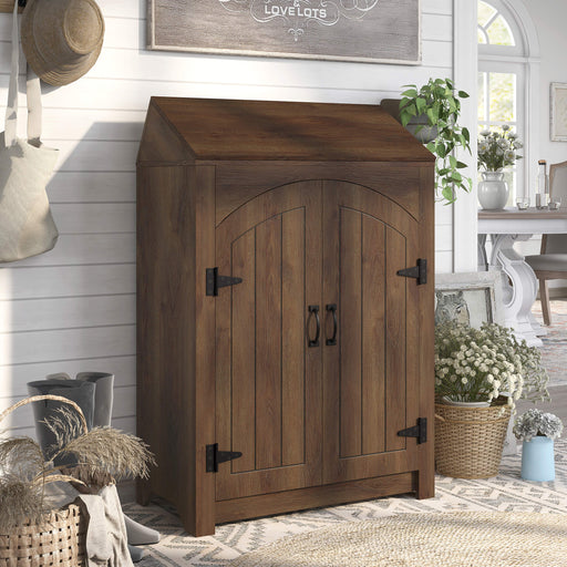 Right-facing transitional distressed walnut finish shoe cabinet with adjustable shelves and flip top shelf in a country farmhouse style entryway foyer. Rustic black door pulls and black hinges.